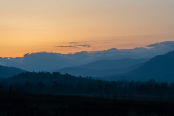 Warm sunrise silhouetting layered mountain ridges above Cades Cove in Great Smoky Mountains National Park